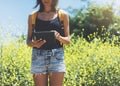 Hipster texting message on tablet or technology, mock up of blank screen. Girl using computer on yellow flowers background close Royalty Free Stock Photo