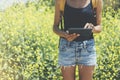 Hipster texting message on tablet or technology, mock up of blank screen. Girl using computer on yellow flowers background close Royalty Free Stock Photo