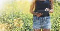 Hipster texting message on tablet or technology, mock up of blank screen. Girl using computer on yellow flowers background close Royalty Free Stock Photo