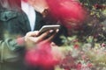 Hipster texting on smartphone or technology, mock up of blank screen. Girl using cellphone on red flowers background. Hands hold Royalty Free Stock Photo