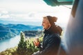Hipster tourist hold in hands mug of hot drink, lonely guy smile enjoy sun flare mountain in auto, happy traveler drink cup of tea