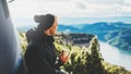 Hipster tourist hold in hands mug of hot drink, lonely smile guy enjoy sun flare mountain in auto, traveler drink cup of tea