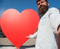 Hipster, tourist with long beard looking at camera, taking selfie photo. Love symbol concept. Man, with beard on