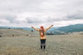 Hipster tourist woman with backpack and sleeping bag walks in the mountains in summer at sunset The girl travels to Royalty Free Stock Photo