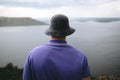 Hipster traveler in purple shirt  and bucket hat standing on top of rock mountain with amazing view on river. Young brutal guy Royalty Free Stock Photo