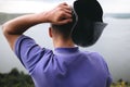 Hipster traveler in purple shirt and bucket hat standing on top of rock mountain with amazing view on river. Young brutal guy Royalty Free Stock Photo