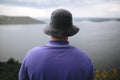 Hipster traveler in purple shirt  and bucket hat standing on top of rock mountain with amazing view on river. Young camper guy Royalty Free Stock Photo