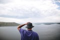 Hipster traveler in purple shirt  and bucket hat standing on top of rock mountain with amazing view on river. Young camper guy Royalty Free Stock Photo