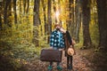 Hipster traveling loving couple at fall forest with sunshine light background. Autumnal golden leaves of trees in forest