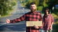 Hipster try to stop car with cardboard sign and thumb