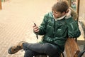 Hipster use smartphone on winter day. Man handsome hold smartphone. Guy sit bench interact smartphone. Man unshaven wear