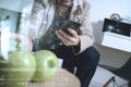 hipster using smart phone for mobile payments online business,sitting on sofa in living room and holding green apple in wooden t