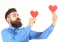 Hipster wears denim shirt. Happy bearded man holds red hearts