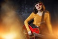 Hipster woman with curly hair play red guitar in neon lights. Rock musician is playing electrical guitar. Royalty Free Stock Photo