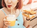 Hipster woman drinks fresh juice and eats a delicious sandwich with a loaf of a checkered Viennese waffle Royalty Free Stock Photo