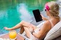 Woman reading something on tablet computer by the pool