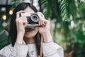 Hipster woman using vintage film camera take a picture of nature landscape plant green tree in the garden