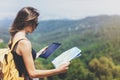 Hipster young girl with backpack enjoying panoramic mountain sea, using map and looking at horizon. Tourist traveler texting Royalty Free Stock Photo