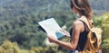 Hipster young girl with bright backpack enjoying panoramic mountain sea, using map and looking distance. Tourist traveler on back Royalty Free Stock Photo