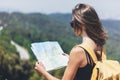 Hipster young girl with bright backpack enjoying panoramic mountain sea, using map and looking distance. Tourist traveler on back Royalty Free Stock Photo