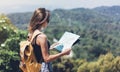 Hipster young girl with bright backpack enjoying panoramic mountain sea, using map and looking distance. Tourist traveler Royalty Free Stock Photo