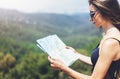 Hipster young girl with bright backpack enjoying panoramic mountain sea, using map and looking distance. Tourist traveler Royalty Free Stock Photo