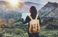 Hipster young girl with bright backpack enjoying sunset on peak of foggy mountain, looking a map and poining hand. Tourist travel Royalty Free Stock Photo
