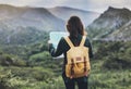 Hipster young girl with bright backpack enjoying sunset on peak of foggy mountain, looking a map and poining hand. Tourist travel Royalty Free Stock Photo