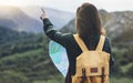 Hipster young girl with bright backpack enjoying sunset on peak of foggy mountain, looking a map and poining hand. Tourist travel Royalty Free Stock Photo
