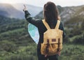 Hipster young girl with bright backpack enjoying sunset on peak of foggy mountain, looking a map and poining hand. Tourist travele Royalty Free Stock Photo