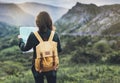 Hipster young girl with bright backpack enjoying sunset on peak of foggy mountain, looking a map and poining hand. Tourist travele Royalty Free Stock Photo