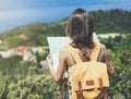 Hipster young girl with bright backpack looking at a map and poining hand the travel plan. View from the back of the tourist trave Royalty Free Stock Photo