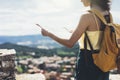 Hipster young girl with bright backpack looking at a map and poining hand the travel plan. View from the back of the tourist trave Royalty Free Stock Photo