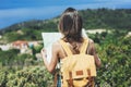 Hipster young girl with bright backpack looking at a map and poining hand the travel plan. View from the back of the tourist Royalty Free Stock Photo
