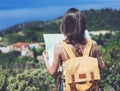 Hipster young girl with bright backpack looking at a map and poining hand the travel plan. View from the back of the tourist Royalty Free Stock Photo