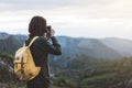 Hipster young girl with bright backpack taking photo of amazing landscape sunset on vintage camera on peak of foggy mountain mock Royalty Free Stock Photo