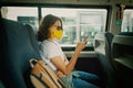 Hipster young girl in a protective mask on her face in a public transport bus with a smartphone in her hands