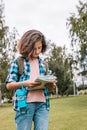 Hipster young girl travels around the city. Cute brunette teen girl looks at the map. Traveling in summer vacation. Vertical shot