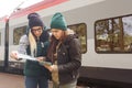 Hipster young girls with backpack and map wait for the Train. Women traveling alone at train station, travel concept Royalty Free Stock Photo