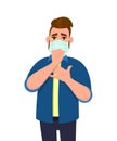 Hipster young man covering face with medical mask and coughing wile holding hand on chest. Trendy person suffering with virus