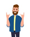 Hipster young man gesturing, doing or making rock and roll symbol or sign with hands up with crazy expression. Modern lifestyle.