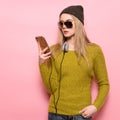 Hipster young woman using cell phone and selecting music to listen on headphones. Royalty Free Stock Photo