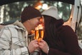 Hipsters on a date in winter kiss and drink champagne