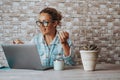 Hipter young woman talking in video call conference onine on laptop. People at work with computer. Bricks background and happy