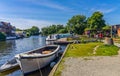 Small hire boat moored up on the River Bure in front of the Kings Head pub in the village of Hoveton and Wroxham, Norfolk, UK