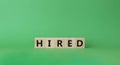 Hired symbol. Wooden cubes with word Hired. Beautiful green background. Hired concept. Copy space Royalty Free Stock Photo