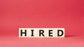 Hired symbol. Wooden cubes with word Hired. Beautiful red background. Hired concept. Copy space Royalty Free Stock Photo