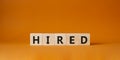 Hired symbol. Wooden cubes with word Hired. Beautiful orange background. Hired concept. Copy space Royalty Free Stock Photo