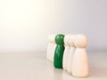 Hiring and leadership selection concept. A row of wooden dolls with one green colour. Royalty Free Stock Photo