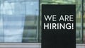 We Are Hiring! on a sign outside a modern glass office building Royalty Free Stock Photo